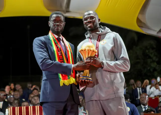 Le président sénégalais Bassirou Diomaye Faye et le capitaine Khalidou Koulibaly tenant le trophée de la CAN