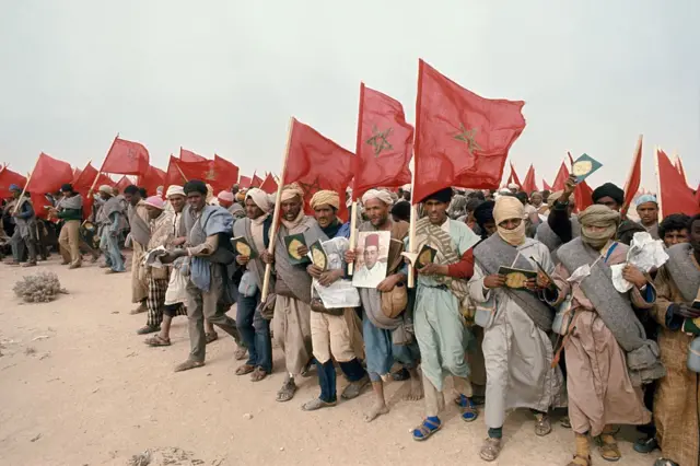 Participants à la Marche verte de 1975, brandissant des drapeaux marocains et des portraits du roi Hassan II.